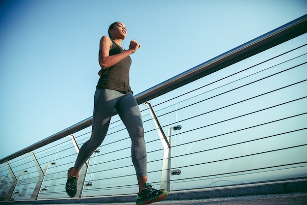 Jonge sportvrouw geniet ervan om overdag alleen op de brug te rennen