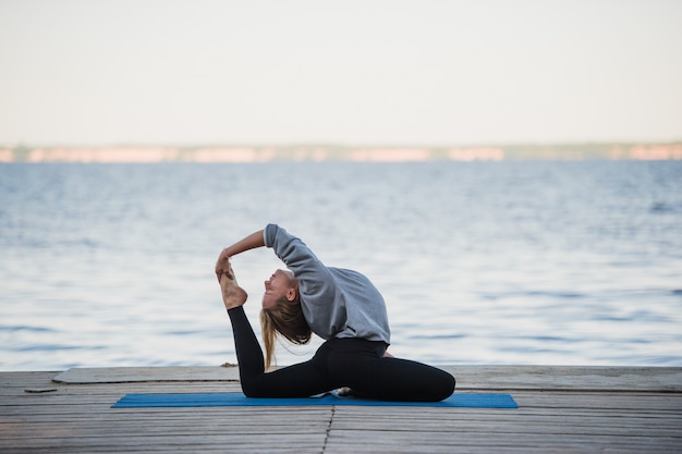 Jonge sportvrouw het beoefenen van yoga op het strand