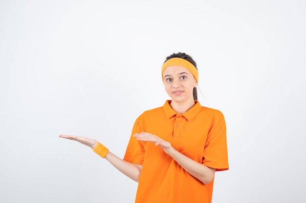 jonge sportvrouw in oranje outfit staan en poseren.