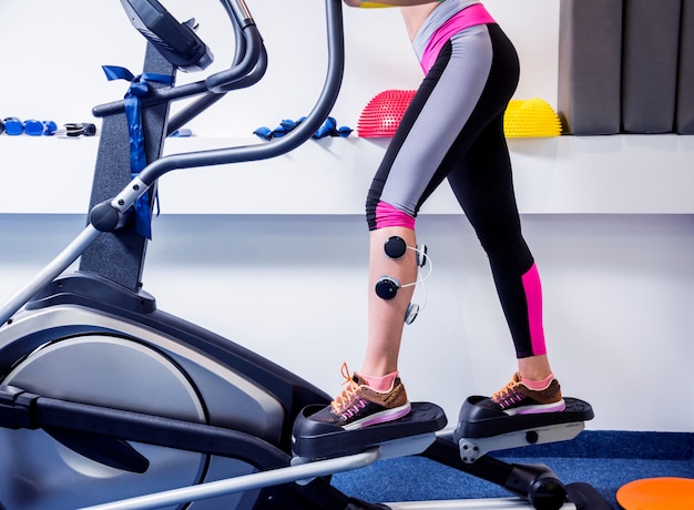 Jonge sportvrouw met elektrostimulator op de spieren van de benen.