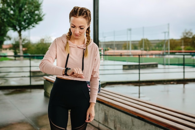 Jonge sportvrouw op zoek naar activiteitenarmband buitenshuis