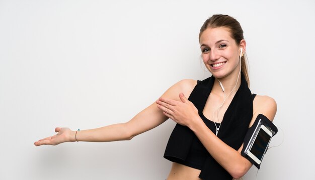 Foto jonge sportvrouw over geïsoleerde witte muur die handen uitbreiden aan de kant voor het uitnodigen om te komen