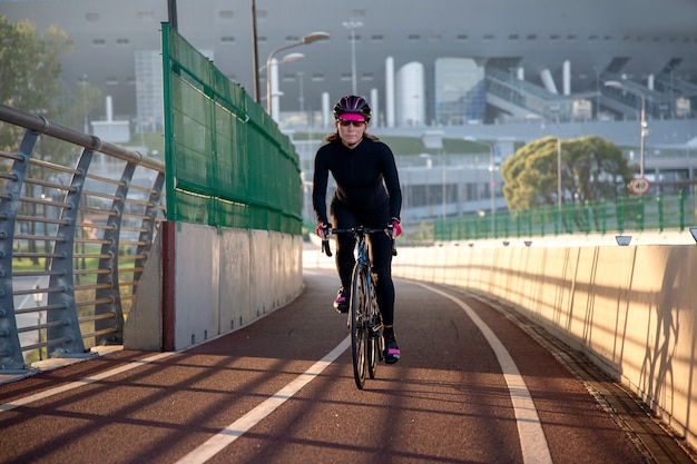 Jonge sportvrouw prachtig verlicht door de zon fietst