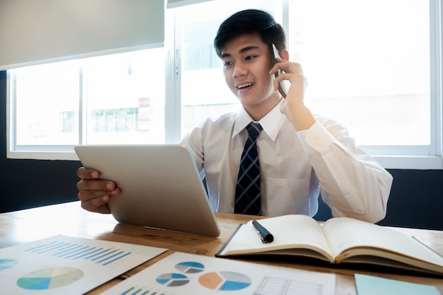 Jonge startende bedrijfsberoeps die aan een cliënt op zijn cellphone spreekt.