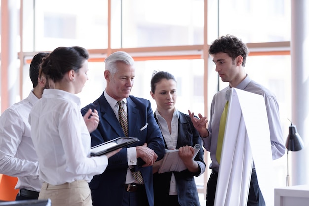 jonge startende zakenman die presentatie van project maakt aan senior investior, groep zakenmensen die aantekeningen maken en plannen maken op witte flip-board en tabletcomputer