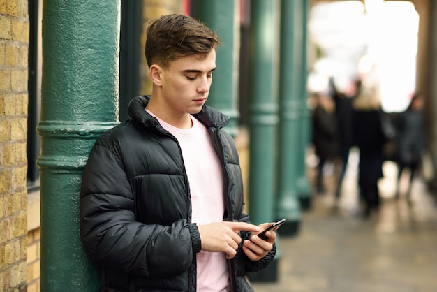 Jonge stedelijke man met behulp van smartphone op stedelijke achtergrond.