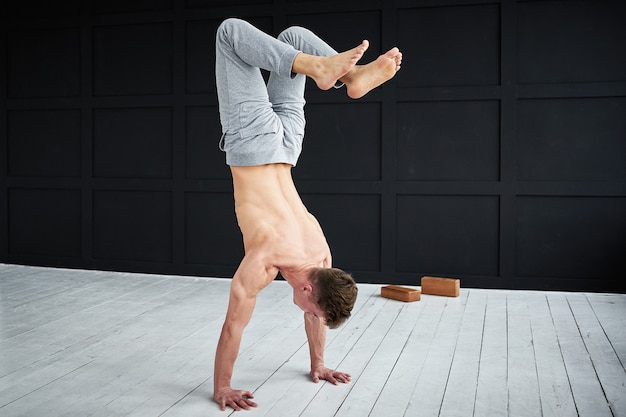 Jonge sterke shirtless man beoefent yoga in de yogastudio