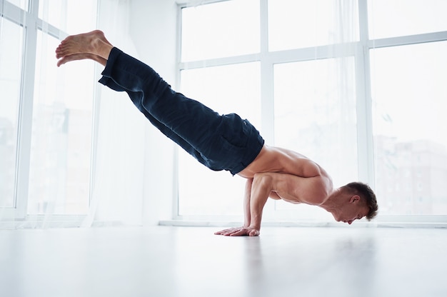 Jonge sterke shirtless man beoefent yoga in de yogastudio