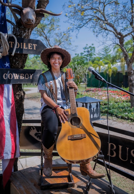 Jonge stijlvolle cowgirl glimlach met gitaar op lente weide in het park.