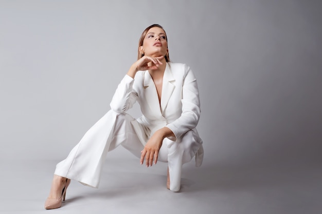 Jonge stijlvolle dame in een wit broekpak, portret in de studio.