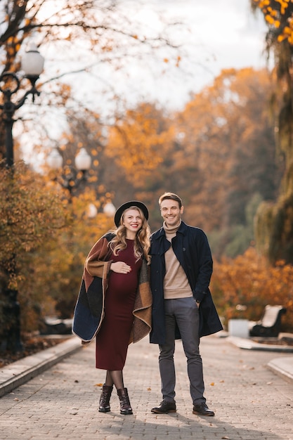 Jonge stijlvolle paar verliefd op een herfst stadspark gelukkig stijlvolle man en mooie zwangere vrouw i...