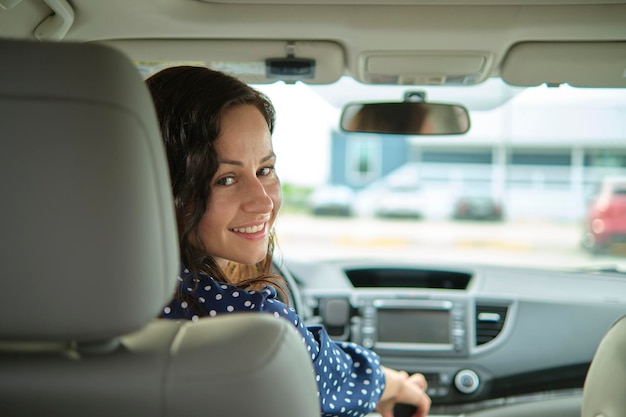 Jonge stijlvolle vrouw bestuurder zit achter het stuur van haar auto Rijden voertuig concept