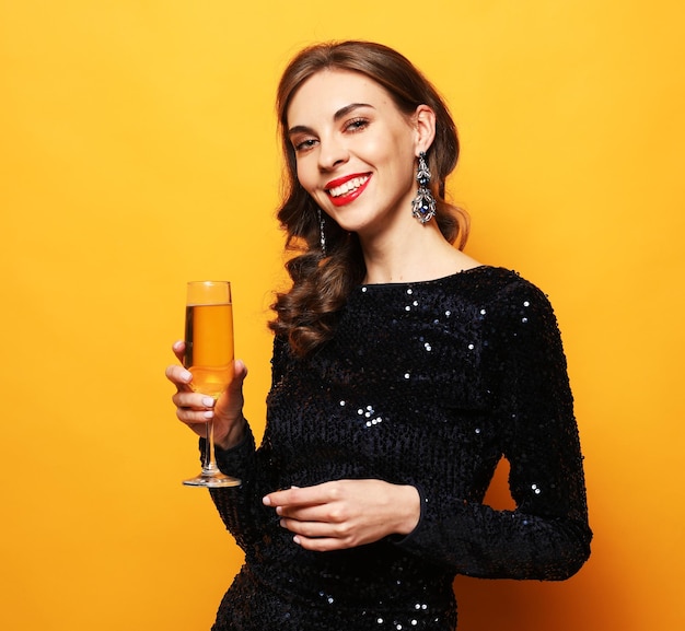 Jonge stijlvolle vrouw die champagne drinkt en nieuwjaar viert in avondjurk