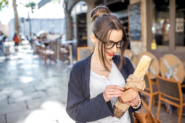 Jonge stijlvolle vrouw die een frans stokbrood koopt dat op straat in de stad lyon staat