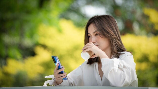 Jonge stijlvolle vrouw die koffie drinkt en een papieren beker gebruikt en in een park jonge mensen vrouwelijke hand gaat