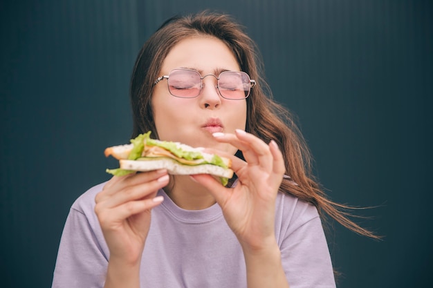 Jonge stijlvolle vrouw genieten van lekkere heerlijke sandwich eten tijdens de lunch