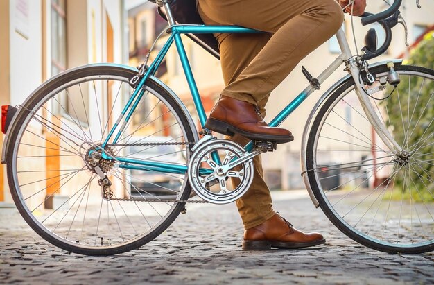 Foto jonge stijlvolle zakenman gaat aan het werk op zijn sport retro fiets op een zonnige dag op een stadsstraat