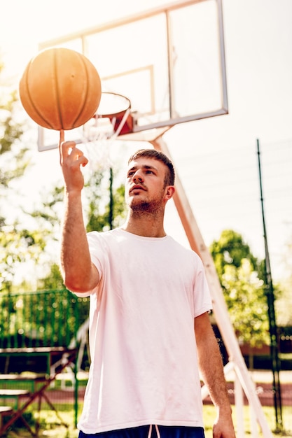 Jonge straatbasketbalspeler die zijn vaardigheden toont. Hij draaiende bal op vinger.