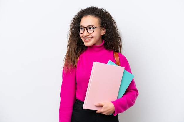 Jonge student Arabische vrouw geïsoleerd op een witte achtergrond op zoek naar de kant en lachend