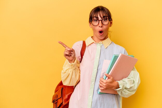 Jonge student argentijnse vrouw geïsoleerd op gele achtergrond wijzend naar de zijkant