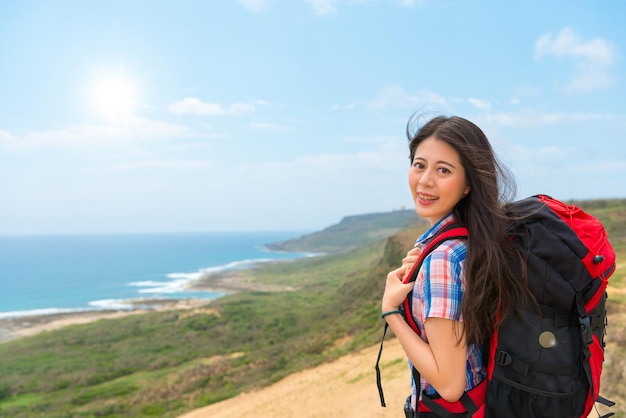 jonge student backpacker gaat naar de prachtige zee land reizen wandelen staande op de heuvels met zon sky copyspace achtergrond in de zomervakantie.