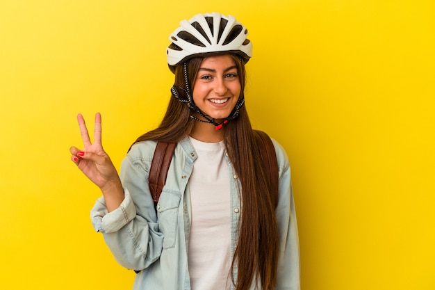 Jonge student blanke vrouw draagt een fietshelm geïsoleerd op gele achtergrond met nummer twee met vingers.