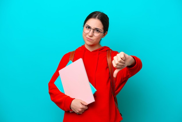 Jonge student blanke vrouw geïsoleerd op blauwe achtergrond met duim omlaag met negatieve expressie