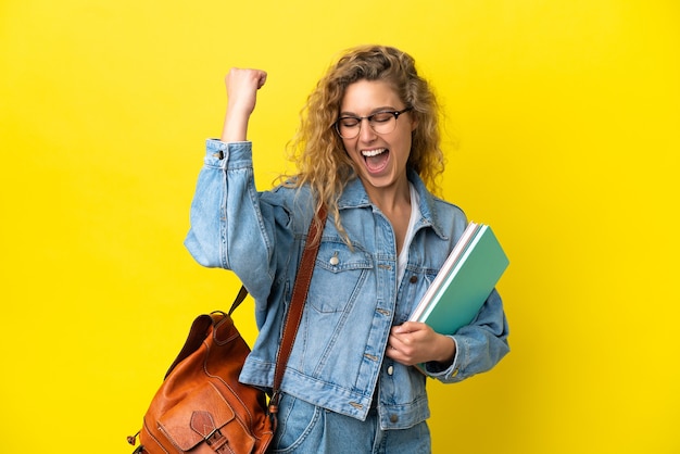 Jonge student blanke vrouw geïsoleerd op gele achtergrond die een overwinning viert