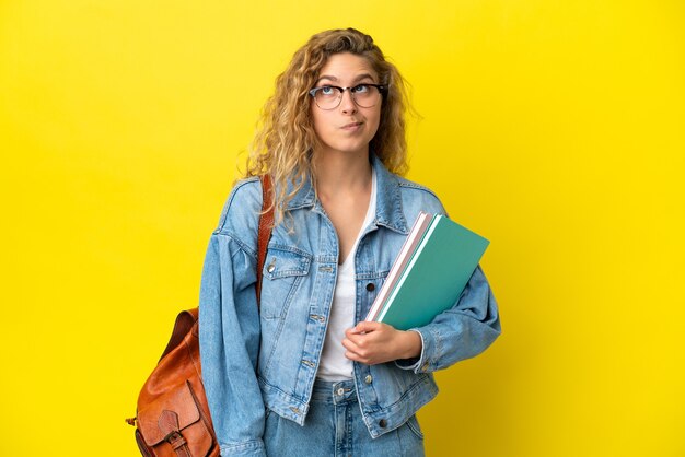 Jonge student blanke vrouw geïsoleerd op gele achtergrond en opzoeken