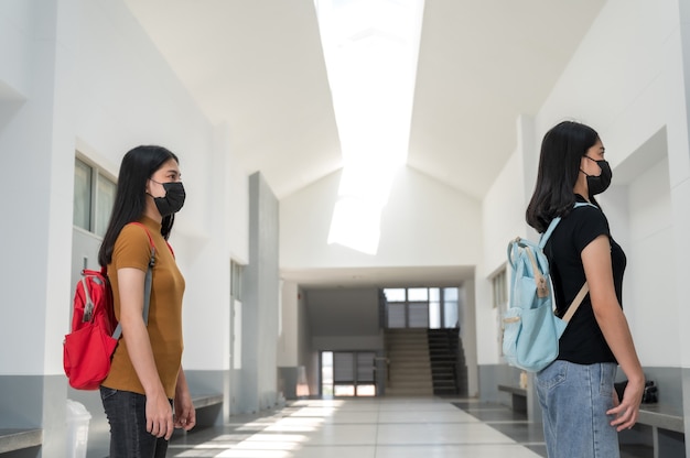 Jonge student die een masker van zwarte stof draagt, terug naar school,