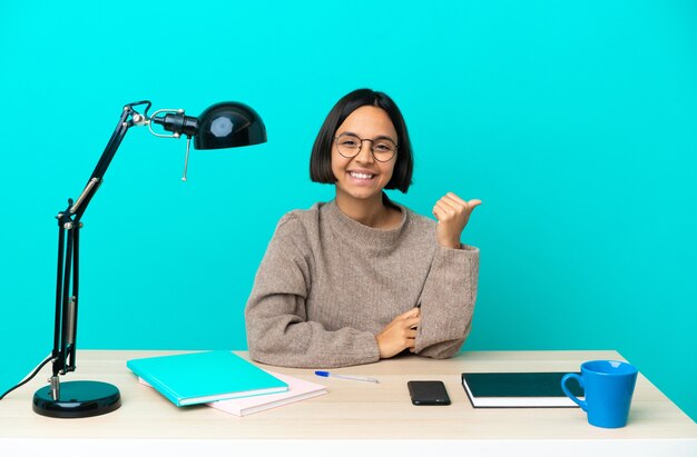 Jonge student gemengd ras vrouw die een tafel bestudeert die naar de zijkant wijst om een product te presenteren