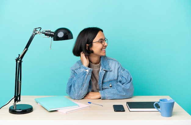 Jonge student gemengd ras vrouw die een tafel bestudeert en een idee denkt