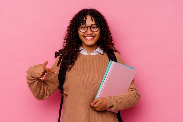 Jonge student gemengd ras vrouw geïsoleerd op roze persoon met de hand wijzend naar een shirt kopieerruimte, trots en zelfverzekerd