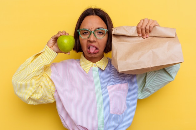 Foto jonge student gemengd ras vrouw lunchen geïsoleerd op gele achtergrond