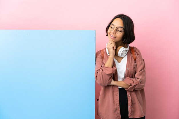 Jonge student gemengd ras vrouw met een grote banner over geïsoleerde achtergrond blij en glimlachen