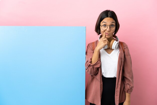 Jonge student gemengd ras vrouw met een grote banner over geïsoleerde achtergrond en denken