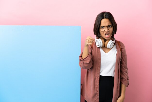 Jonge student gemengd ras vrouw met een grote banner over geïsoleerde achtergrond gefrustreerd en naar voren wijzend