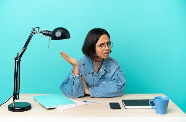 Jonge student gemengd ras vrouw studeren aan een tafel twijfels