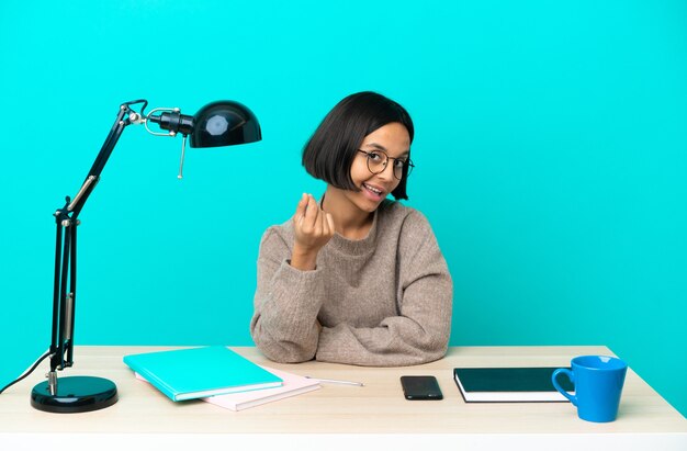 Jonge student gemengd ras vrouw studeren op een tafel geld gebaar maken