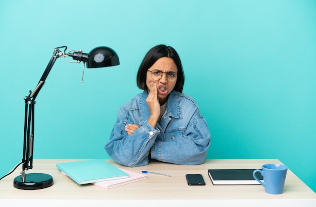 Jonge student gemengd ras vrouw studeren op een tafel met kiespijn