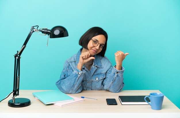 Jonge student gemengd ras vrouw studeren op een tafel naar de kant om een product te presenteren