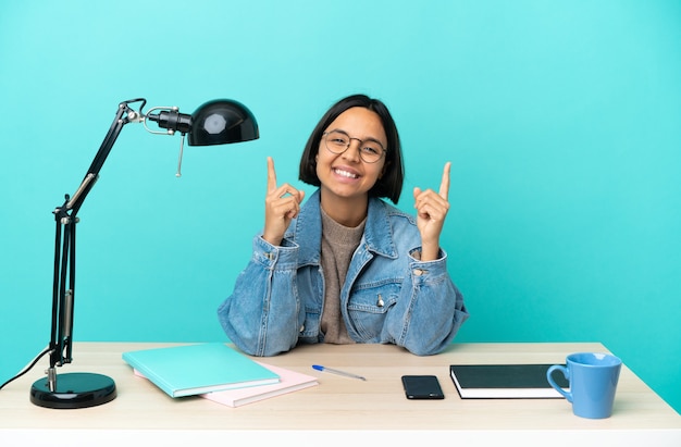 Jonge student gemengd ras vrouw studeren op een tafel wijzend op een geweldig idee