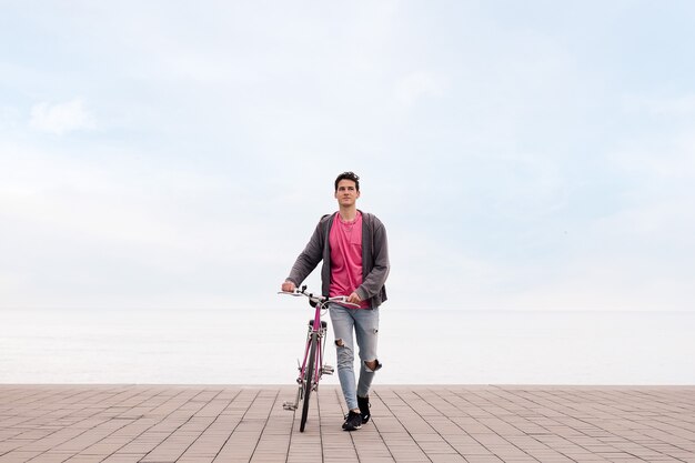 Jonge student loopt terwijl hij een fiets duwt