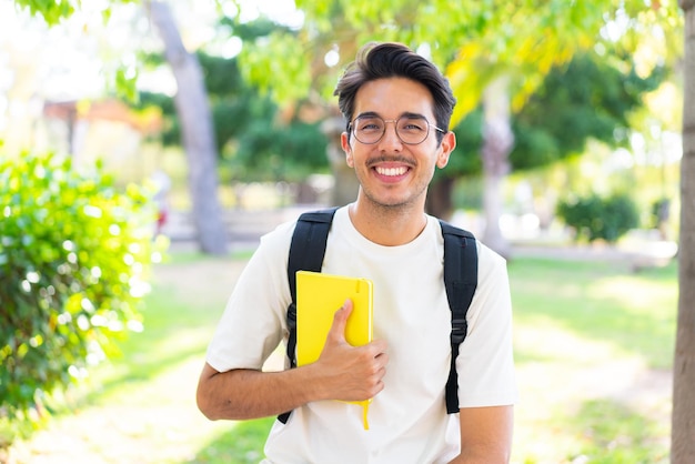 Jonge student man in de buitenlucht met een notitieboekje met gelukkige uitdrukking