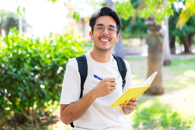 Jonge student man in de buitenlucht met een notitieboekje