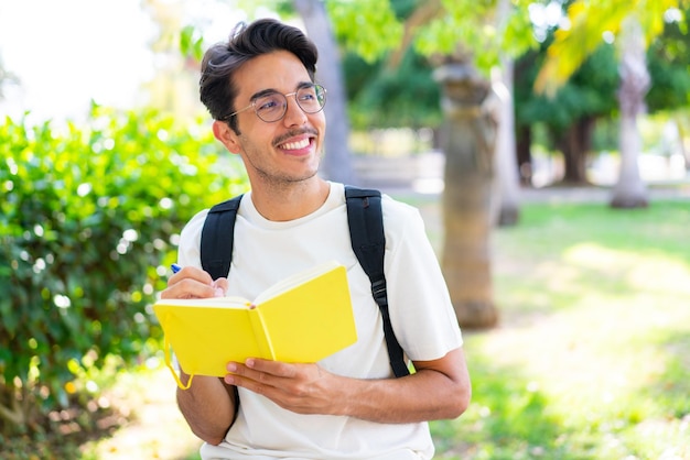 Jonge student man in de buitenlucht met een notitieboekje