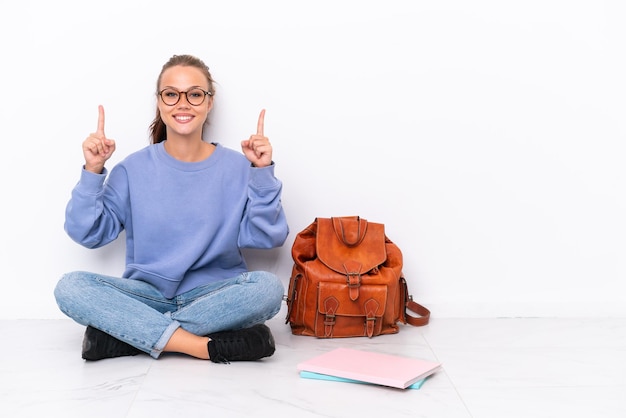 Jonge student meisje zittend op de vloer geïsoleerd op een witte achtergrond met een geweldig idee