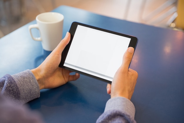 Jonge student met behulp van zijn tablet in café