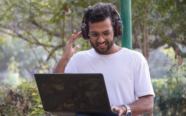 Jonge student met laptop - netwerkprobleem tijdens videogesprek man met laptop