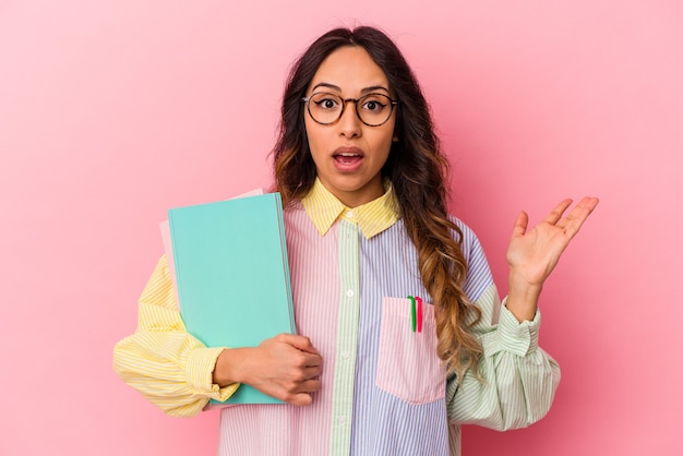 Jonge student Mexicaanse vrouw geïsoleerd op roze achtergrond verrast en geschokt.